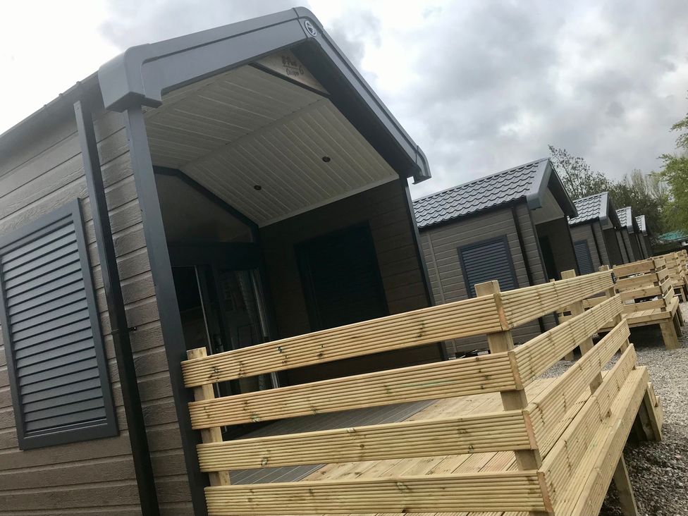 Multiple cabins with wooden decking and shutters at Inverness Lodge in Inverness