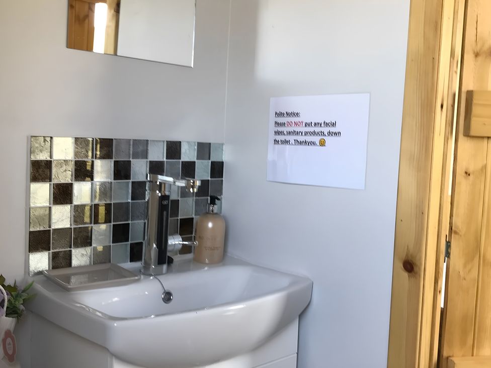 A bathroom with a sink and a notice at Shepherds hut in Dumfries