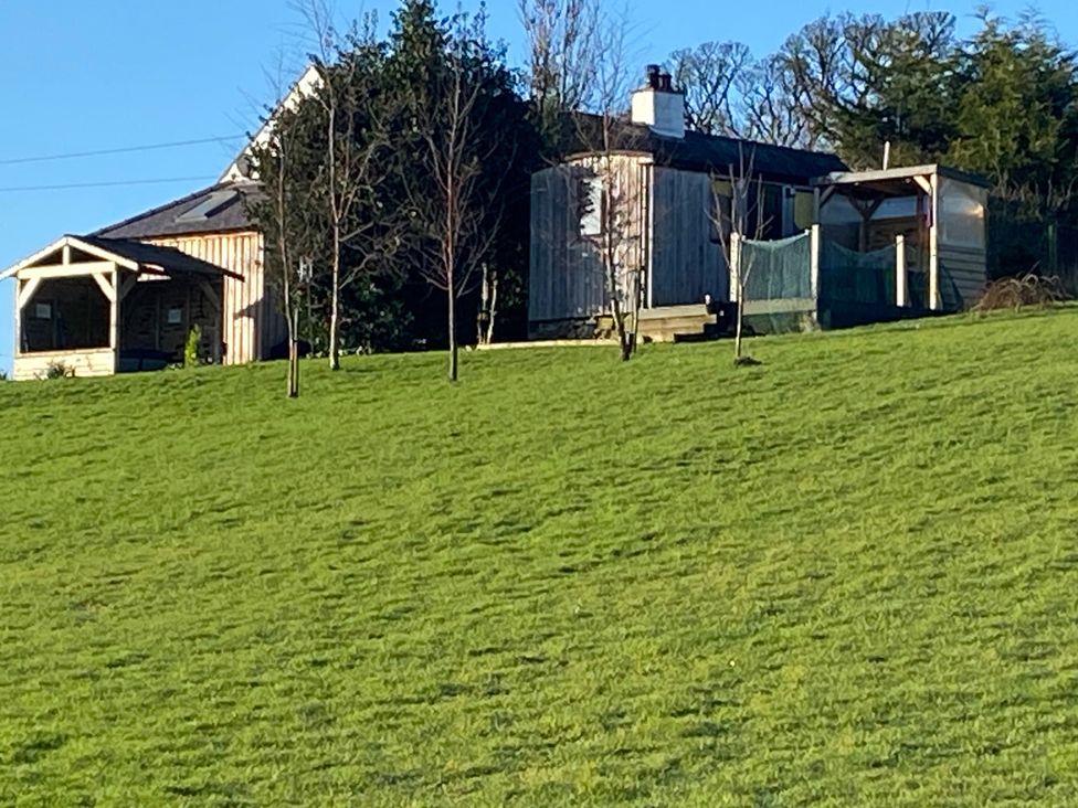 A house with a deck and trees in the yard at Shepherds hut in Dumfries