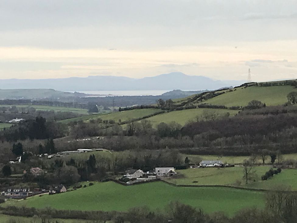 A view of hills and fields with houses in the foreground at Shepherds hut in Dumfries