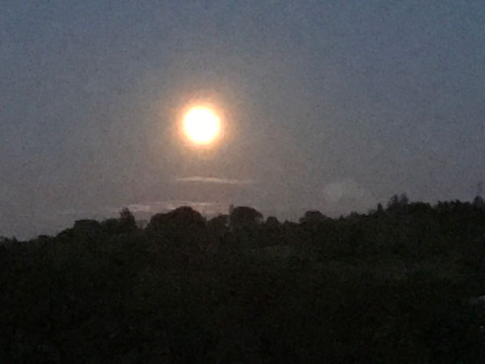 A moon over a landscape with clouds at the night sky