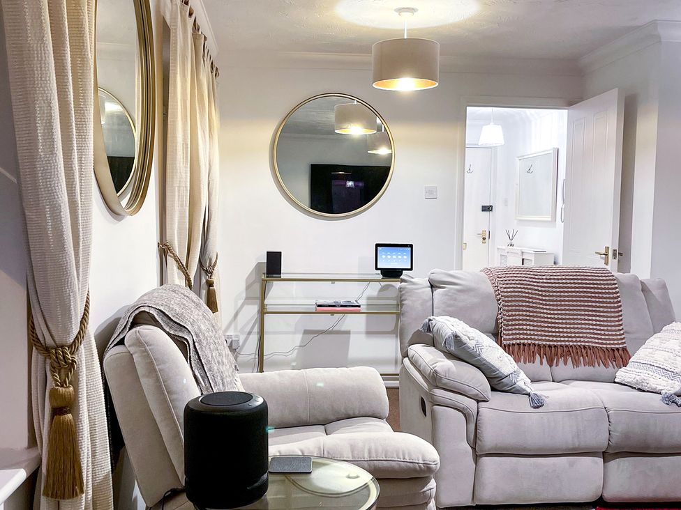 A living room with a sofa and tablet on a shelf at 1-Bed Apt in Rochester, Kent