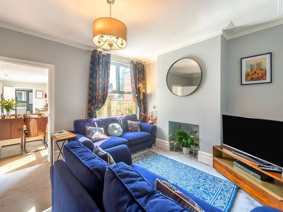 A living room with a sofa, television, and mirror at Love Lane Villa in Lincoln