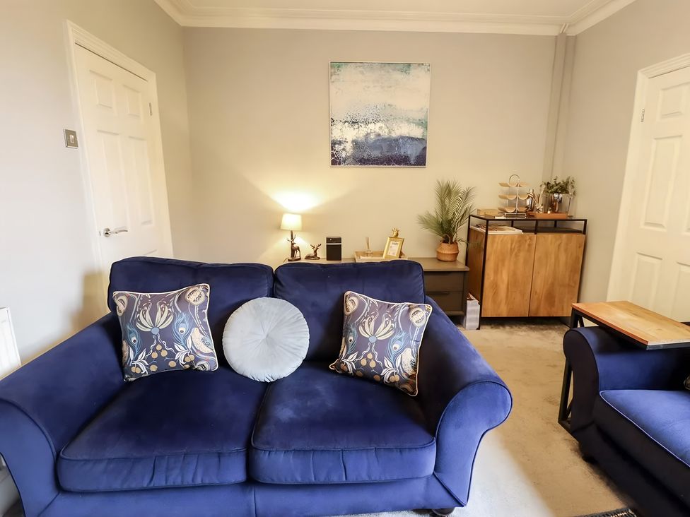 A living room with a blue sofa and artwork on the wall at Love Lane Villa in Lincoln