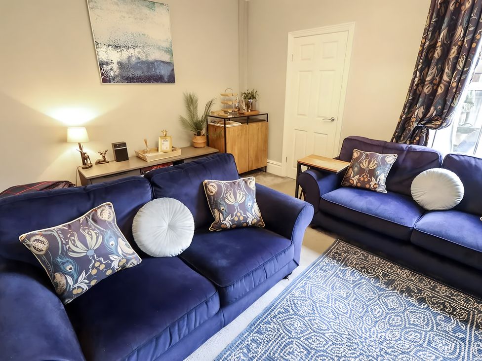 A living room with sofas and a cabinet at Love Lane Villa in Lincoln