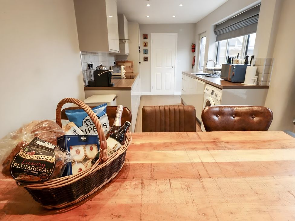 A kitchen with a wooden table and basket of snacks at Love Lane Villa in Lincoln