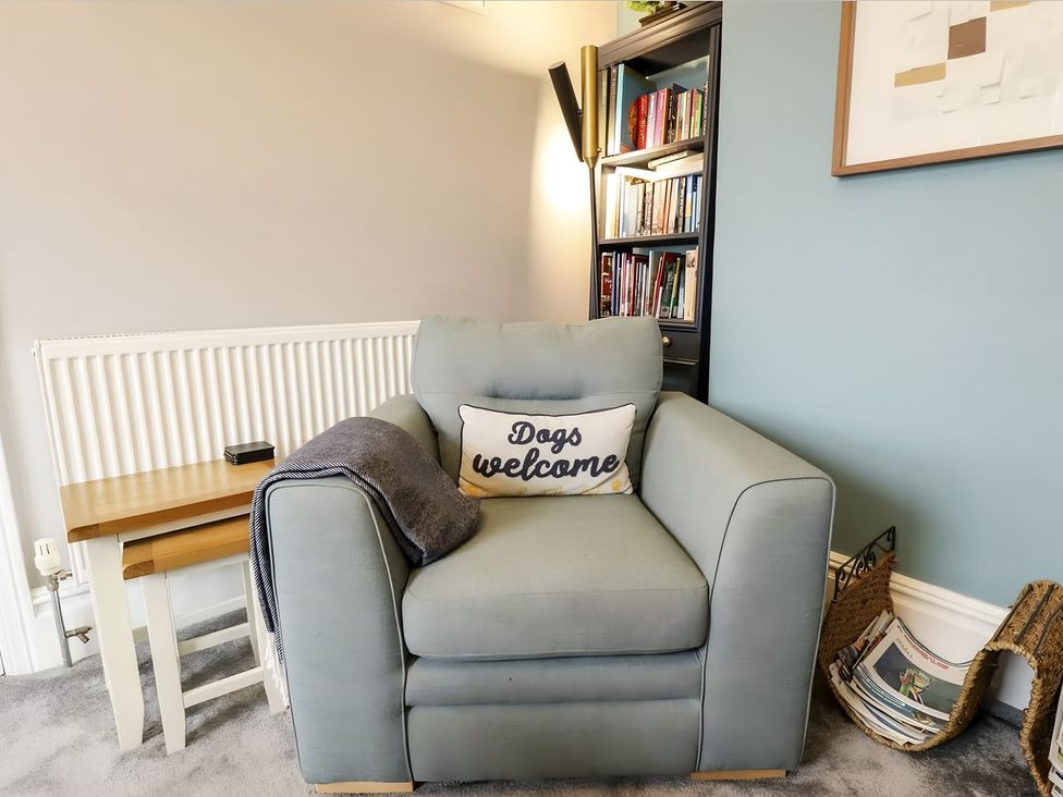 A living room with an armchair and a bookshelf at Love Lane Villa in Lincoln