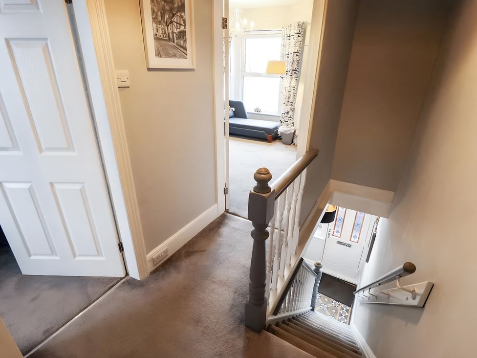 A staircase and hallway with doors leading to a living room and entrance at Love Lane Villa Lincoln