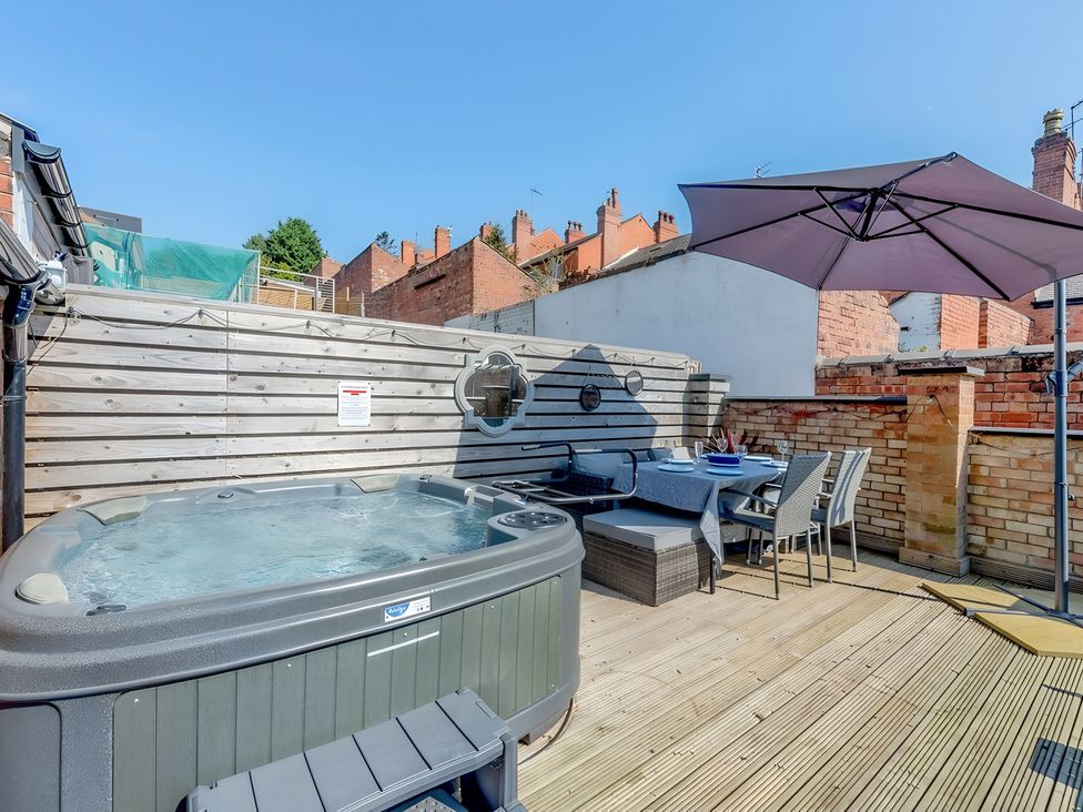 An outdoor patio featuring a hot tub and dining area at Love Lane Villa in Lincoln