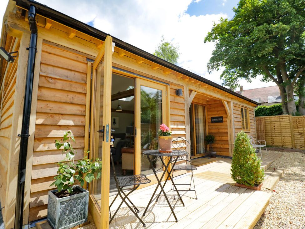 A wooden cabin exterior with outdoor seating at Goose Lodge in Shipston-on-Stour