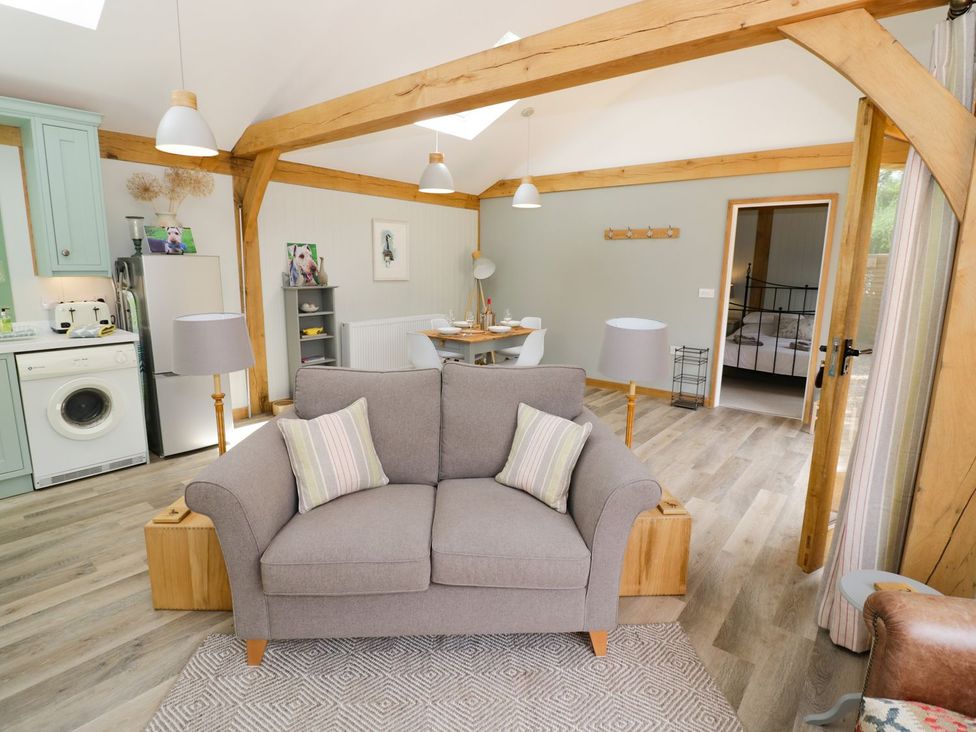 A living room with sofa, table, and kitchen appliances at Goose Lodge in Shipston-on-Stour