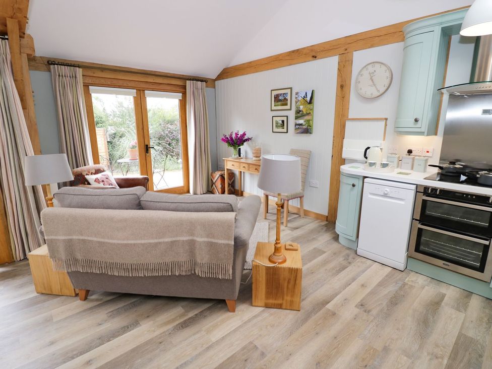 A living room with a sofa and kitchenette at Goose Lodge in Shipston-on-Stour