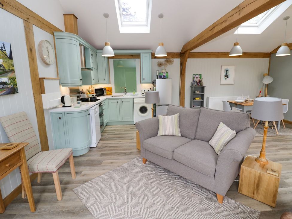 A living room with a sofa and kitchen area at Goose Lodge in Shipston-on-Stour