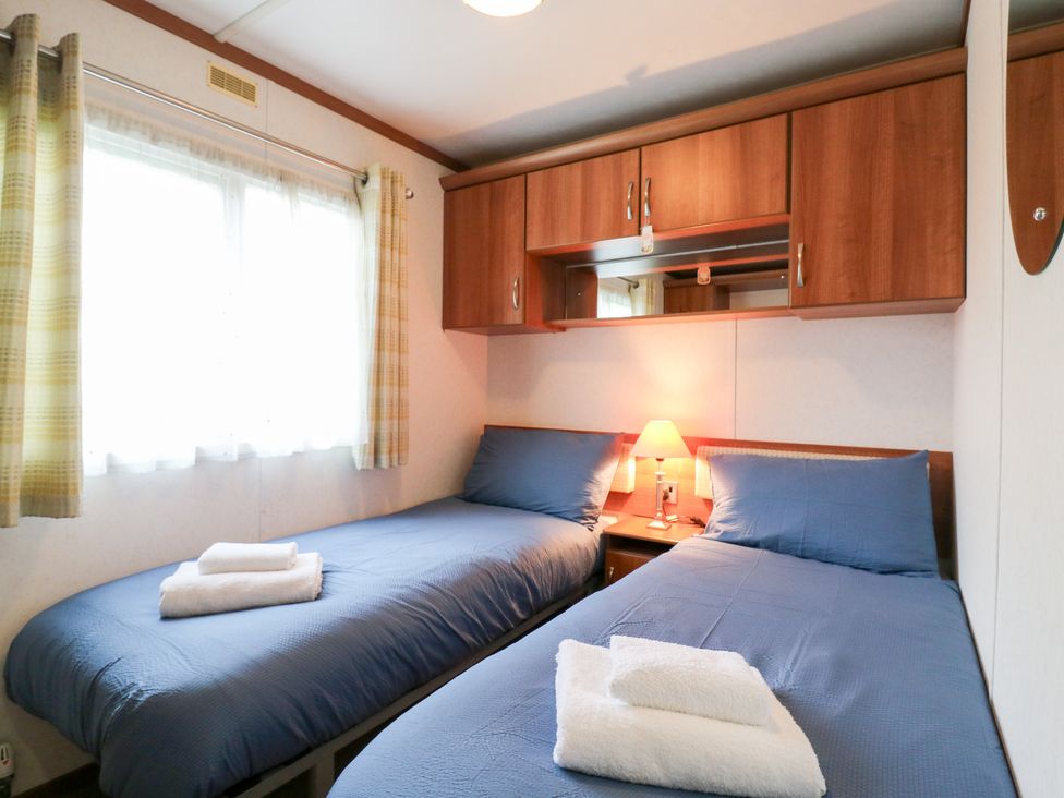 A bedroom with two beds, a lamp, and shelves at No 35 MP Billing Aquadrome Holiday Park