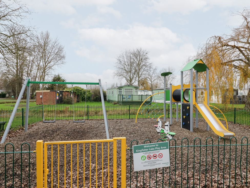 A playground with swings and slide at Kingfisher Lake Play Area