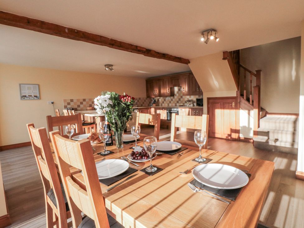 A dining room with a wooden table set for a meal at Millstone Cottage in Sneaton Thorpe near Whitby
