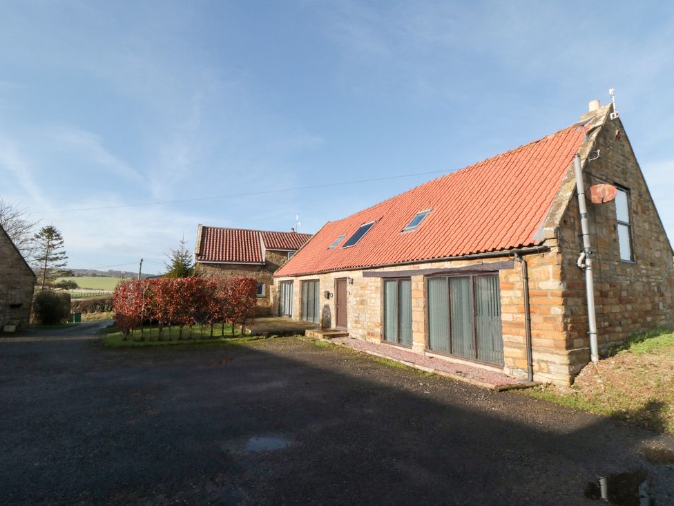 A stone building with a red roof and windows at Millstone Cottage Sneaton Thorpe near Whitby