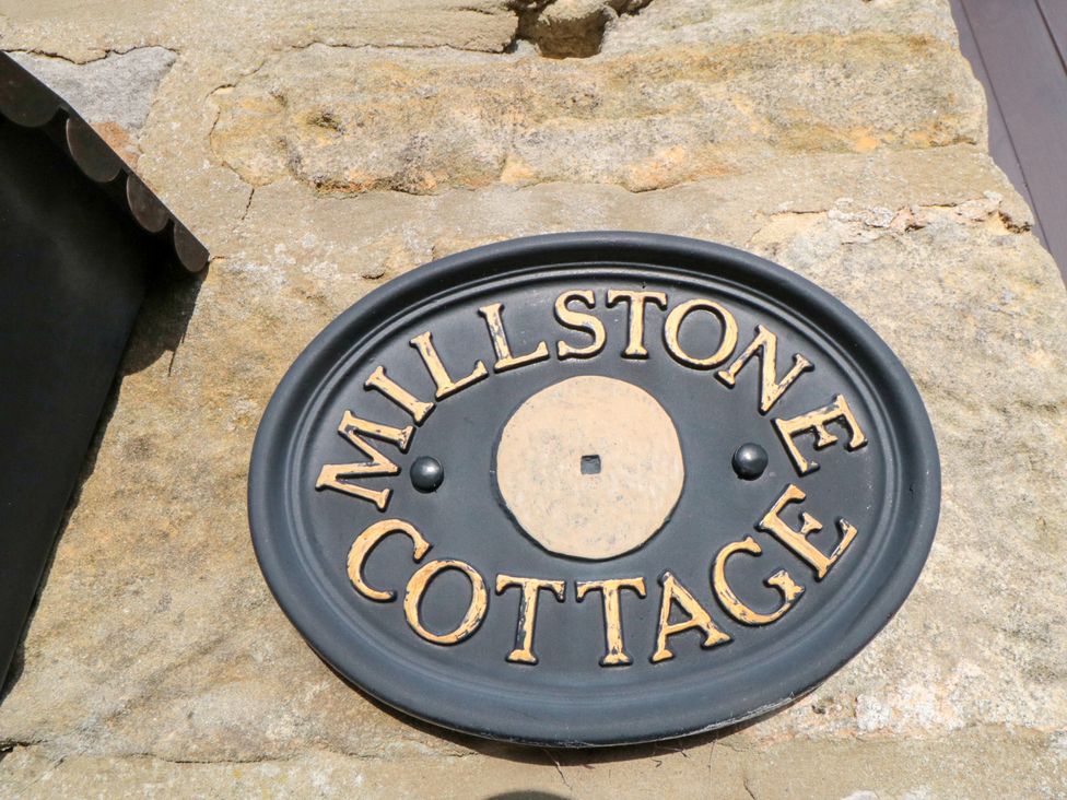 A nameplate that reads Millstone Cottage on a stone wall at Millstone Cottage Sneaton Thorpe near Whitby
