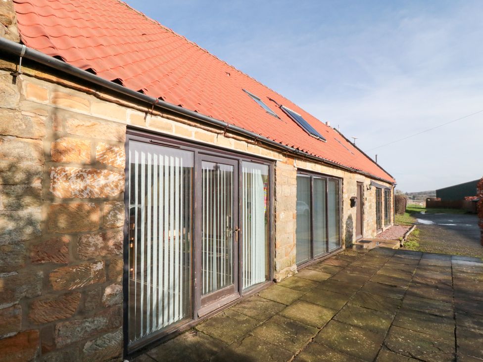 An outdoor area with sliding doors and stone walls at Millstone Cottage Sneaton Thorpe near Whitby