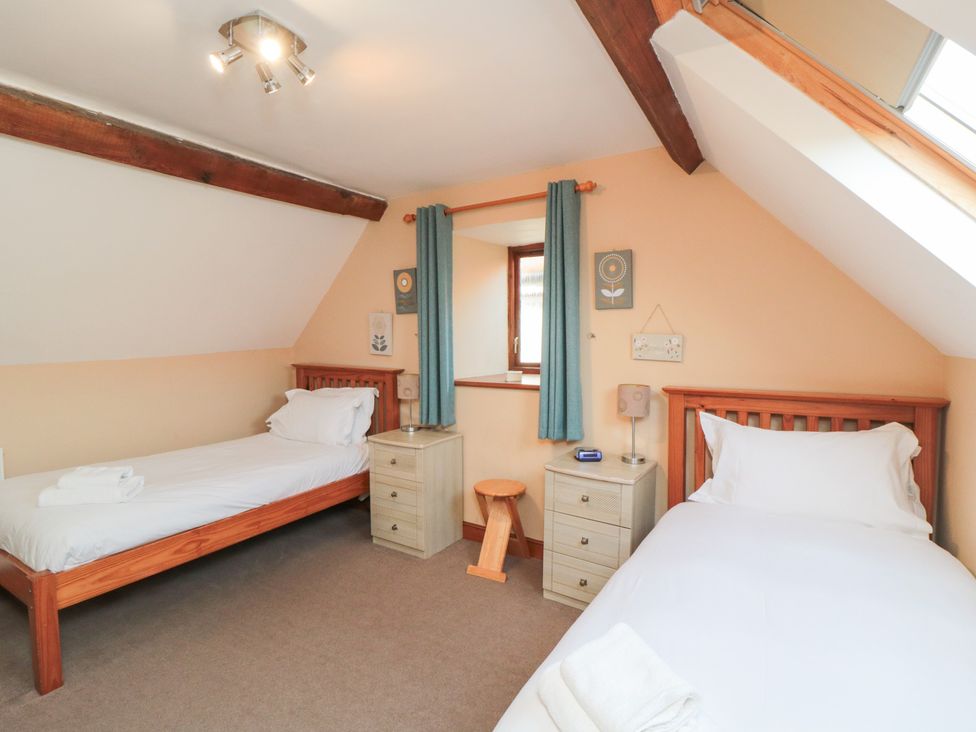 A bedroom with two single beds and a window at Millstone Cottage Sneaton Thorpe near Whitby