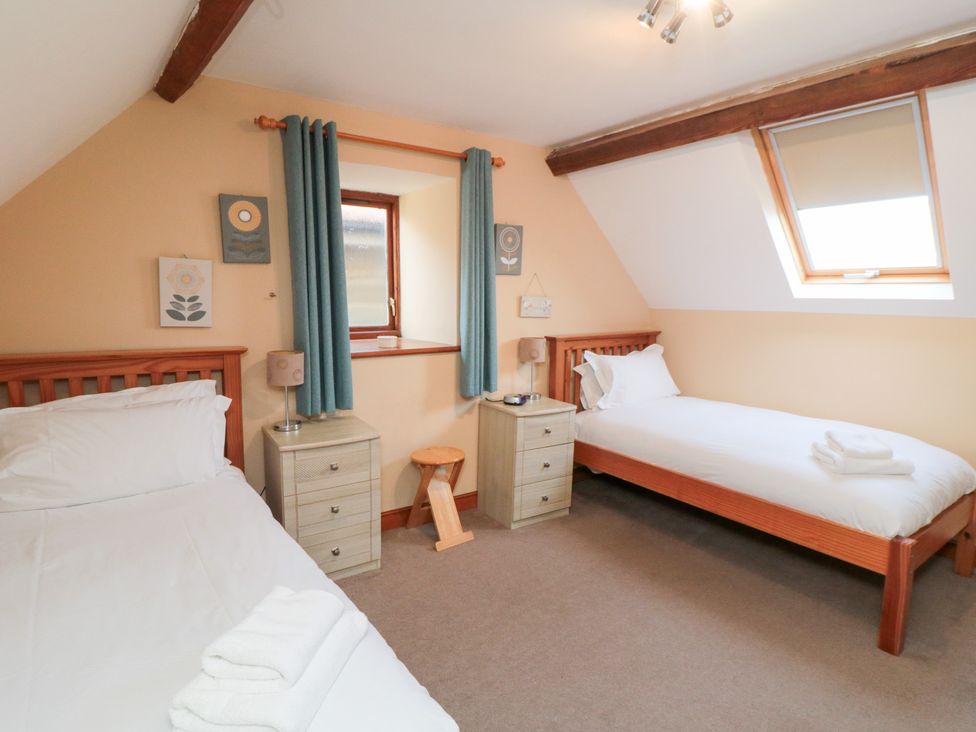 A bedroom with two beds and a nightstand at Millstone Cottage in Sneaton Thorpe near Whitby