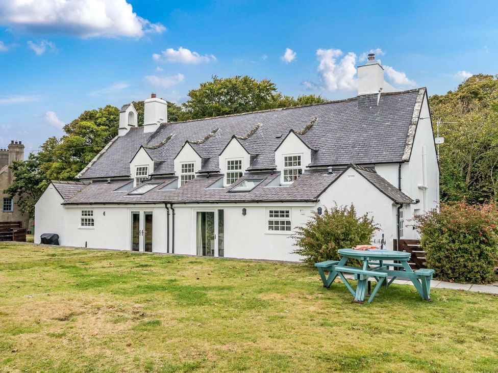 An outdoor view of a house with a picnic table and chairs at Bodior Garden Cottage Bach Holyhead