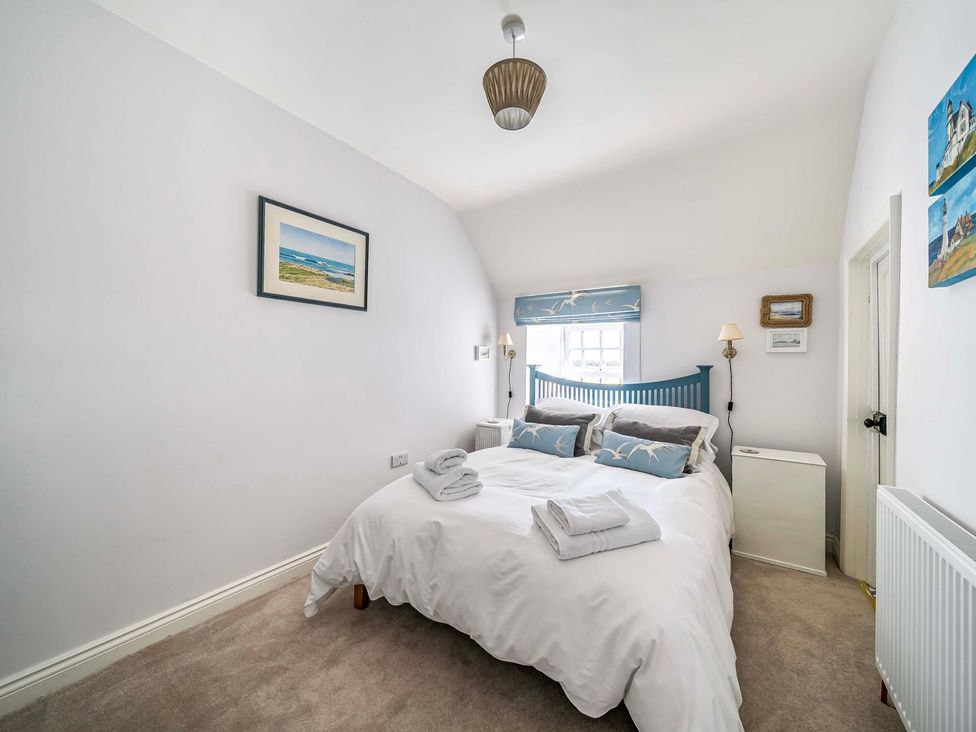 A bedroom with a bed and bedside lamps at Bodior Garden Cottage Bach in Holyhead