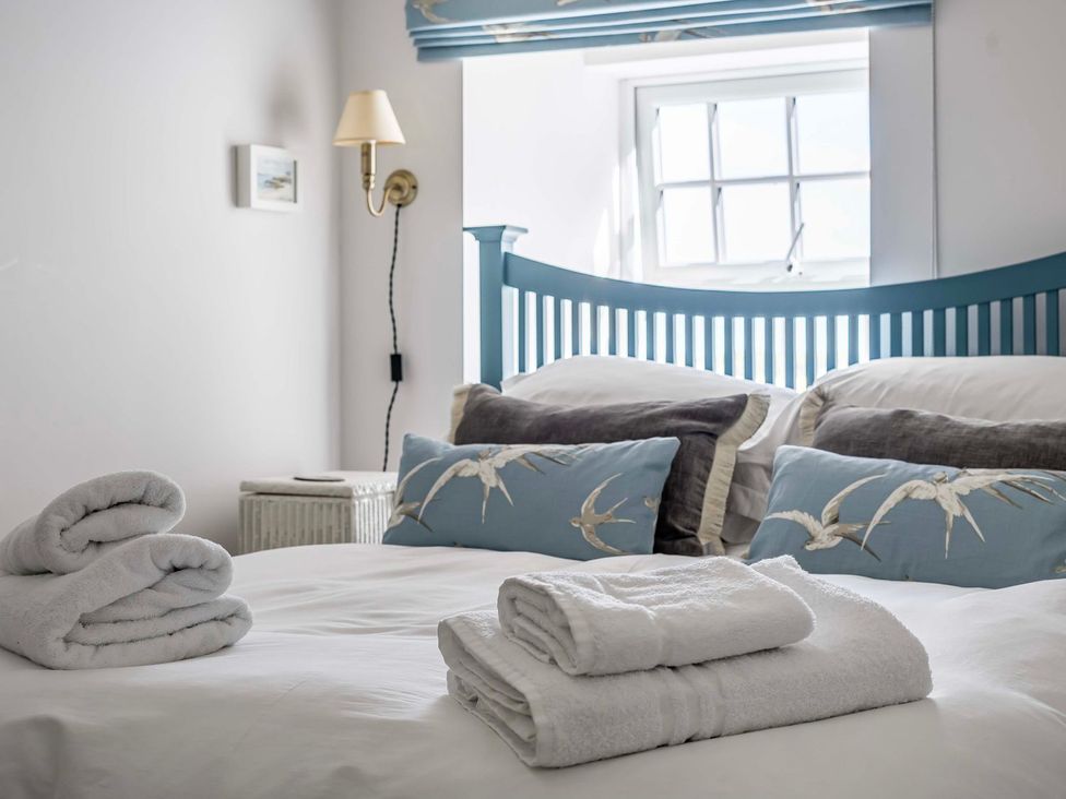 A bedroom with a bed and towels at Bodior Garden Cottage Bach in Holyhead