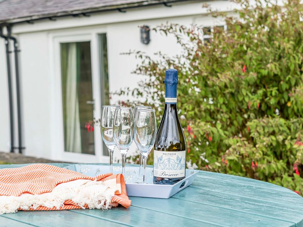 A tray with a bottle of prosecco and glasses on a table at Bodior Garden Cottage Bach Holyhead