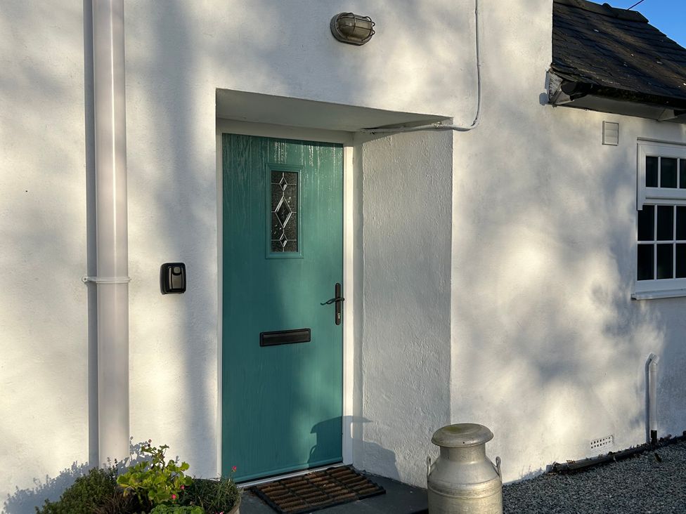 A blue door with a letterbox and light fixture at Bodior Garden Cottage Bach Rhoscolyn
