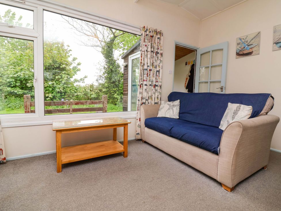 A living room with a sofa and table at Sea Breeze in Welcombe near Morwenstow