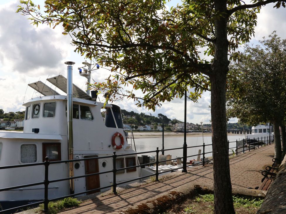 A boat by the water with trees along the walkway at Sea Breeze in Welcombe near Morwenstow