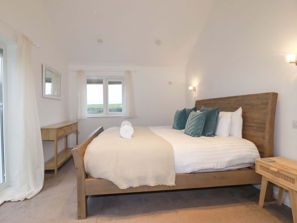 A bedroom with a bed and mirror at Poldreth in Truro