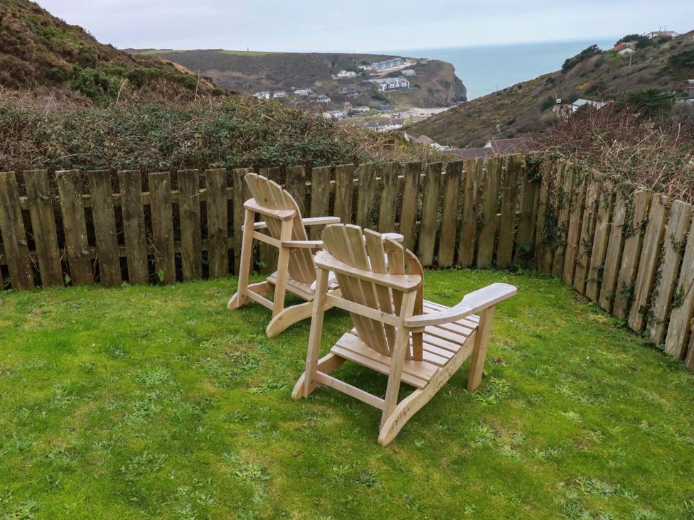 A garden with wooden chairs and a fence overlooking hills at Poldreth in Truro