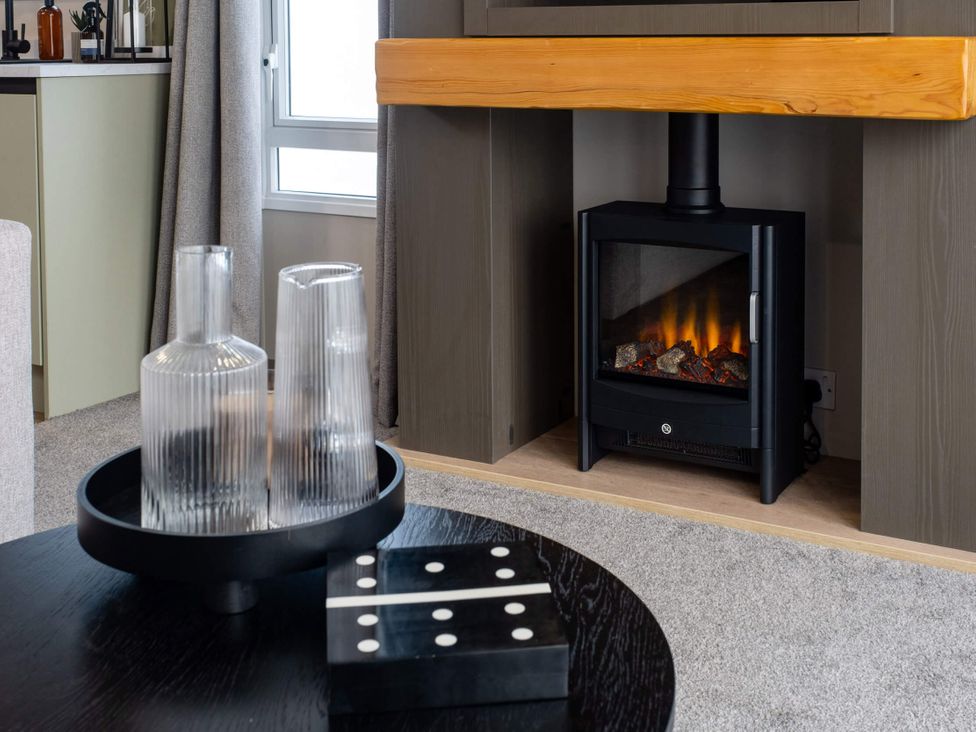 A living room with a fireplace and vases on a table at Arlington 40 x 14 Three Bed in Northwich