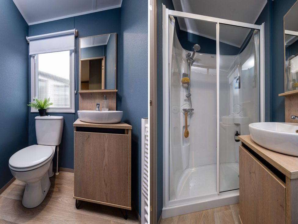 A bathroom with a toilet, sink, shower, and mirror at Arlington 40 x 14 Three Bed in Northwich