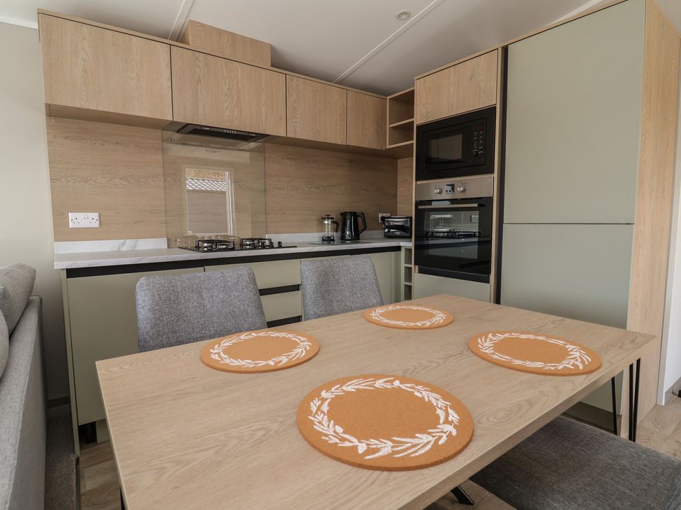 A kitchen with cabinets, appliances and a table at No.6 - The Pines Delamere