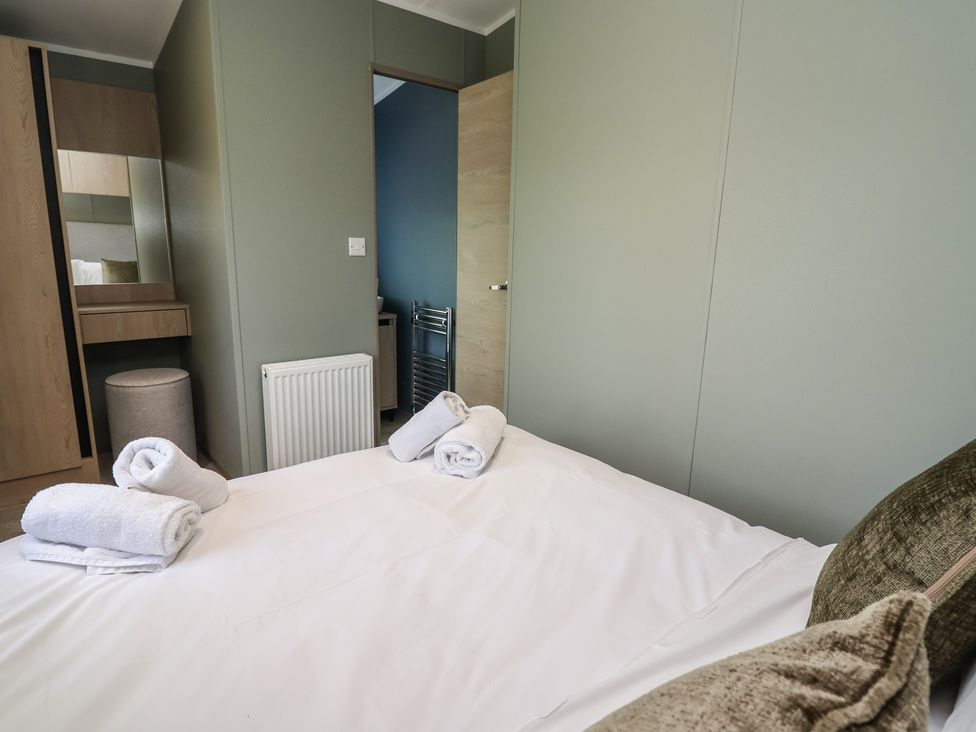 A bedroom with a bed and towels at No.6 - The Pines, Delamere