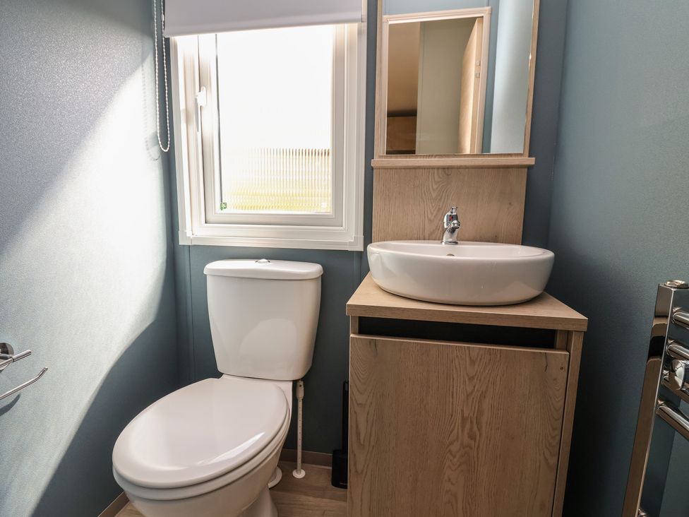 A bathroom with a sink, toilet, and window at No.6 - The Pines in Delamere