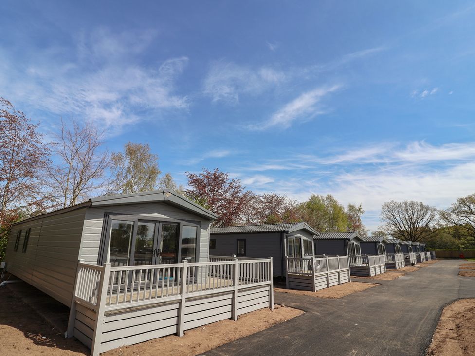 A row of mobile homes with decks in an outdoor area at No.6 - The Pines Delamere