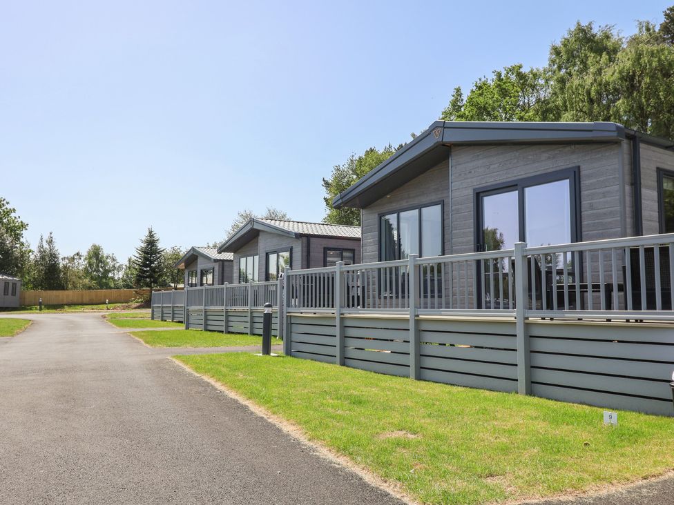 A view of several cabins with decking and a pathway at The Pines 3 Bedrooms Delamere
