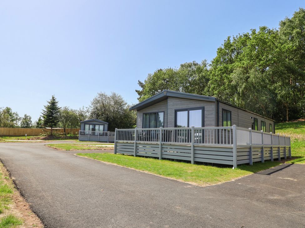 Two cabins with decks and a pathway in an outdoor area at The Pines 3 Bedrooms Delamere