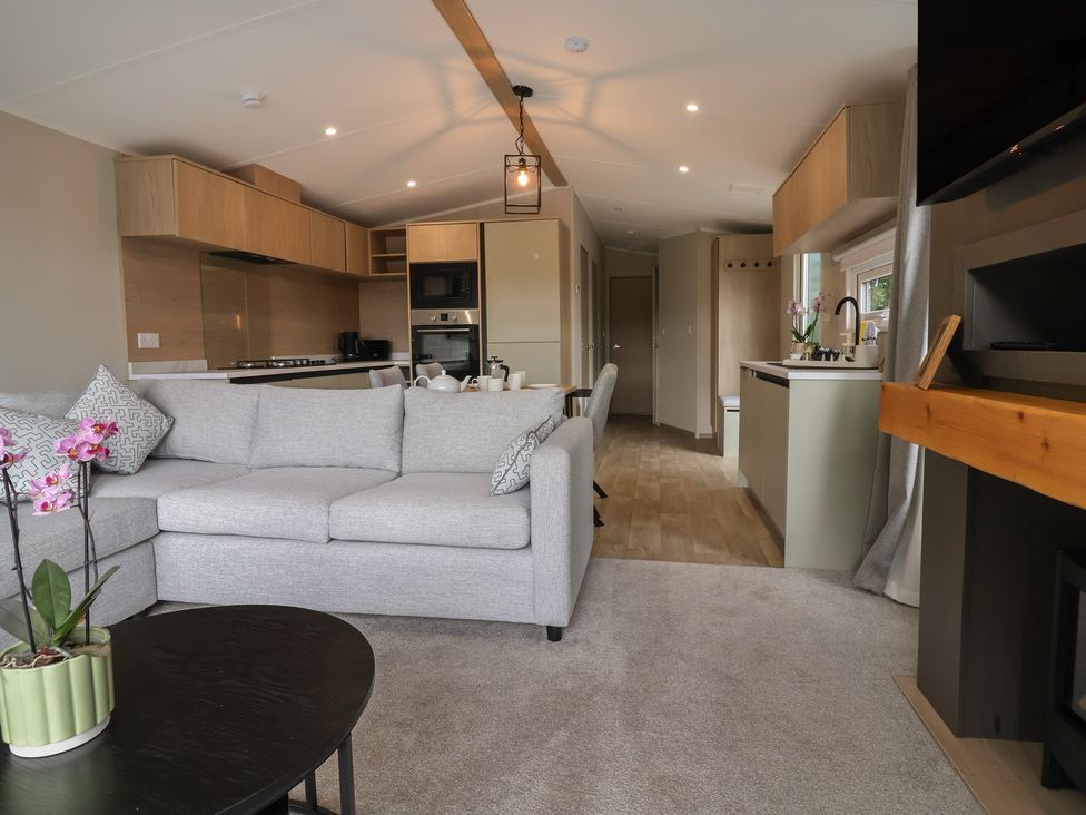 A living room with a sofa and kitchen area at The Pines 3 Bedrooms in Delamere