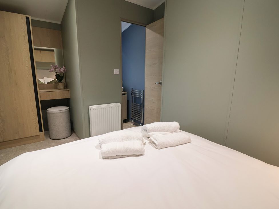 A bedroom with a bed and towels at The Pines 3 Bedrooms in Delamere