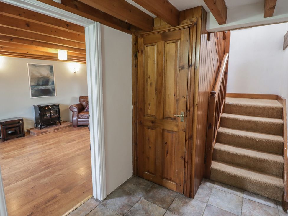 A hallway with a staircase and door at Rhosgranog Cottage, Llandeloy near Solva