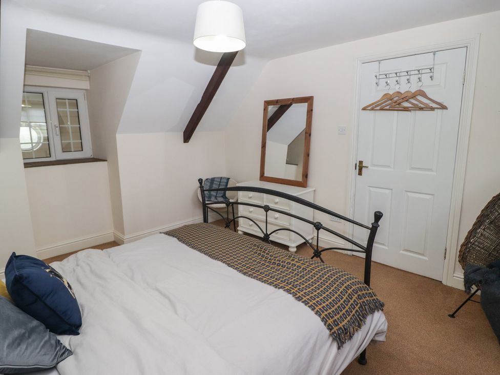 A bedroom with a bed, window, and mirror at Rhosgranog Cottage in Llandeloy near Solva