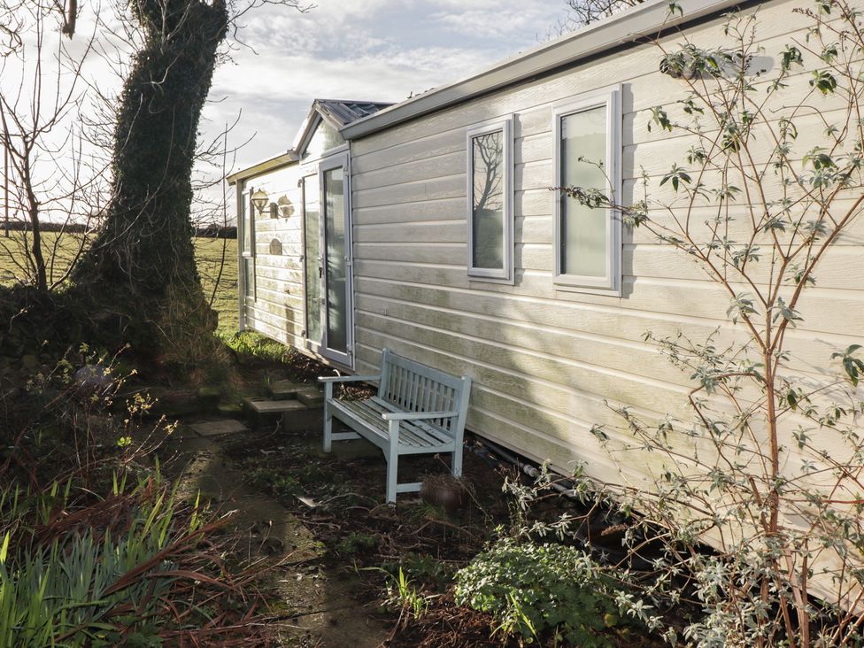An outdoor area with a caravan and a bench at Rhosgranog Caravan Llandeloy near Solva