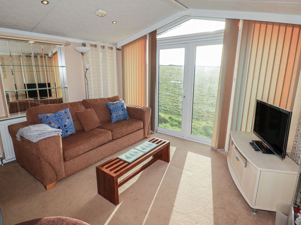 A living room with a sofa and coffee table at Rhosgranog Caravan Llandeloy near Solva