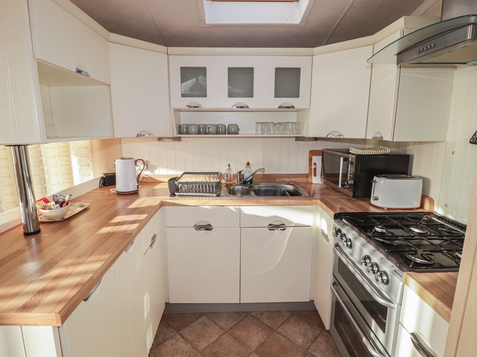 A kitchen with various appliances and cabinets at Rhosgranog Caravan in Llandeloy near Solva