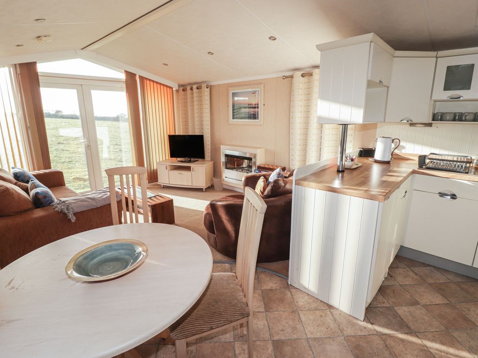 A living room with sofa and kitchen area at Rhosgranog Caravan in Llandeloy near Solva